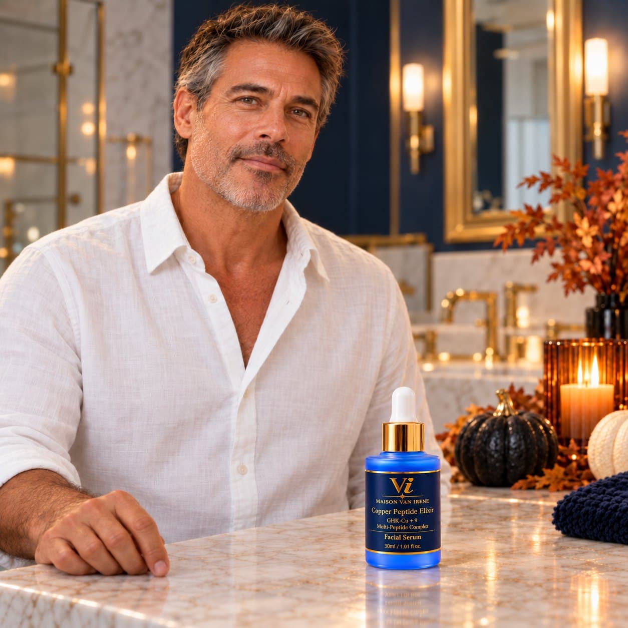 A man at a candlelit marble vanity with the Copper Peptide Elixir, autumn leaves and pumpkins — skincare for men and women