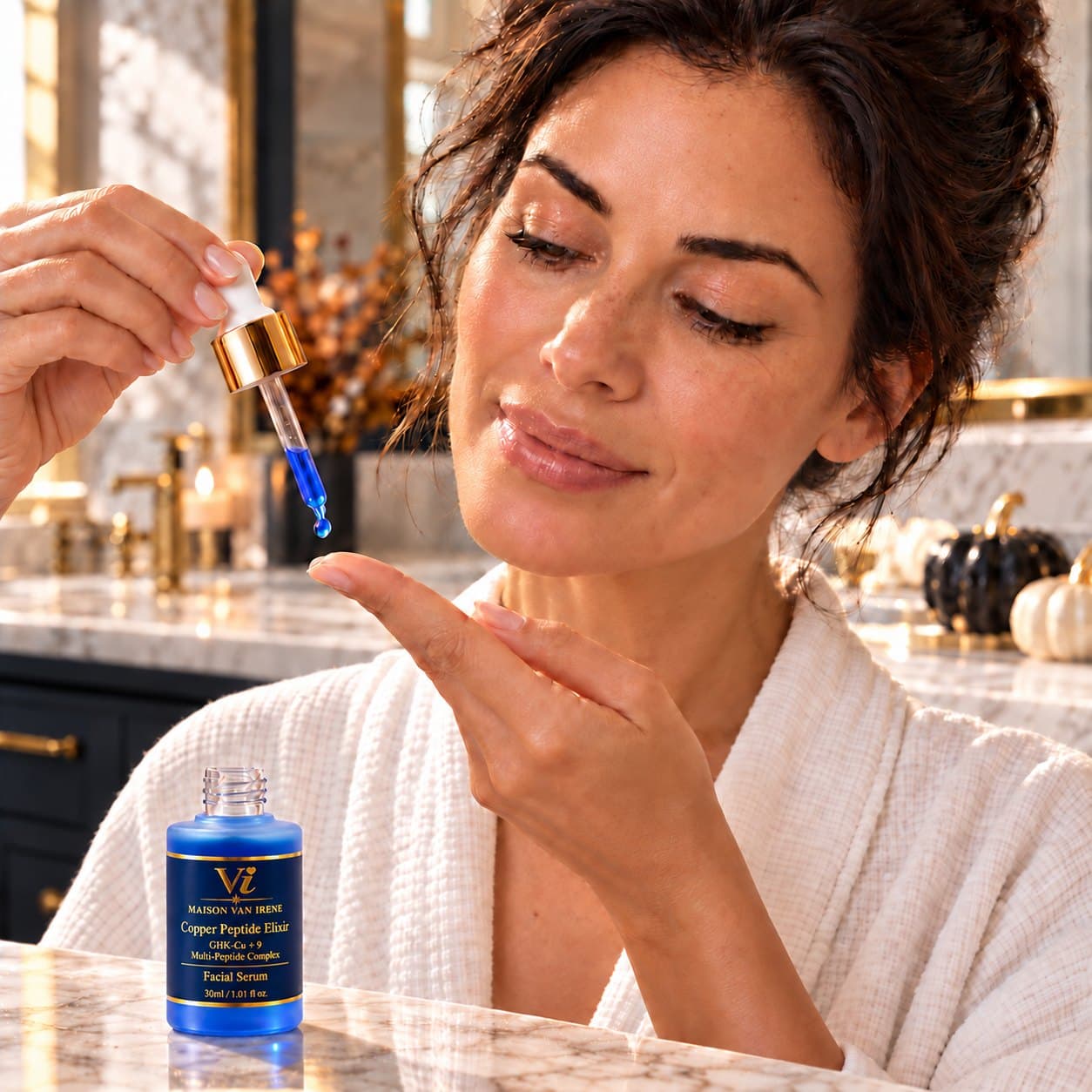 A woman applying a drop of the blue Copper Peptide Elixir from the gold dropper to her fingertip